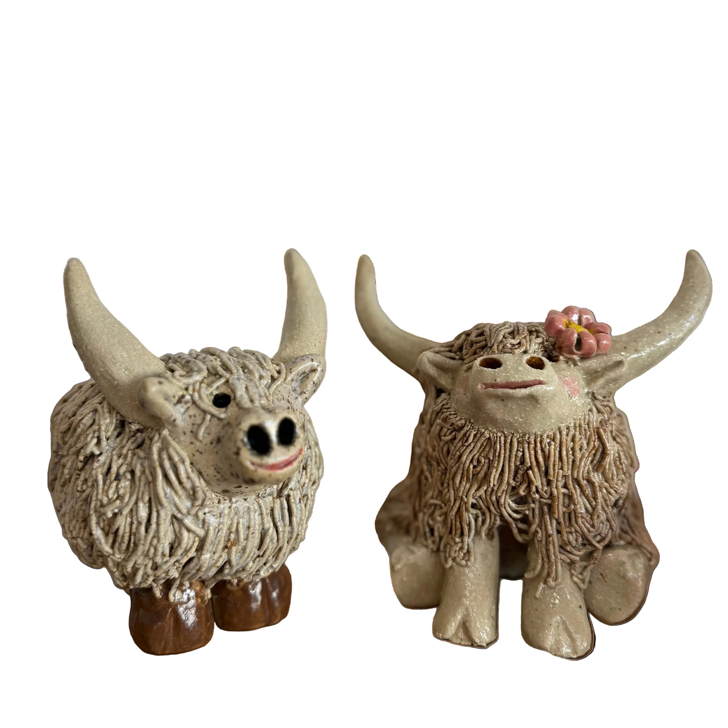 Two ceramic highland cow  figurines with a white background
